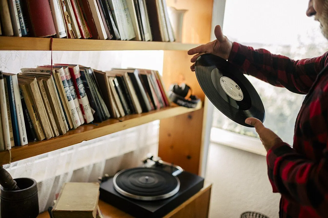 Selecting a vinyl record from a home library shelf