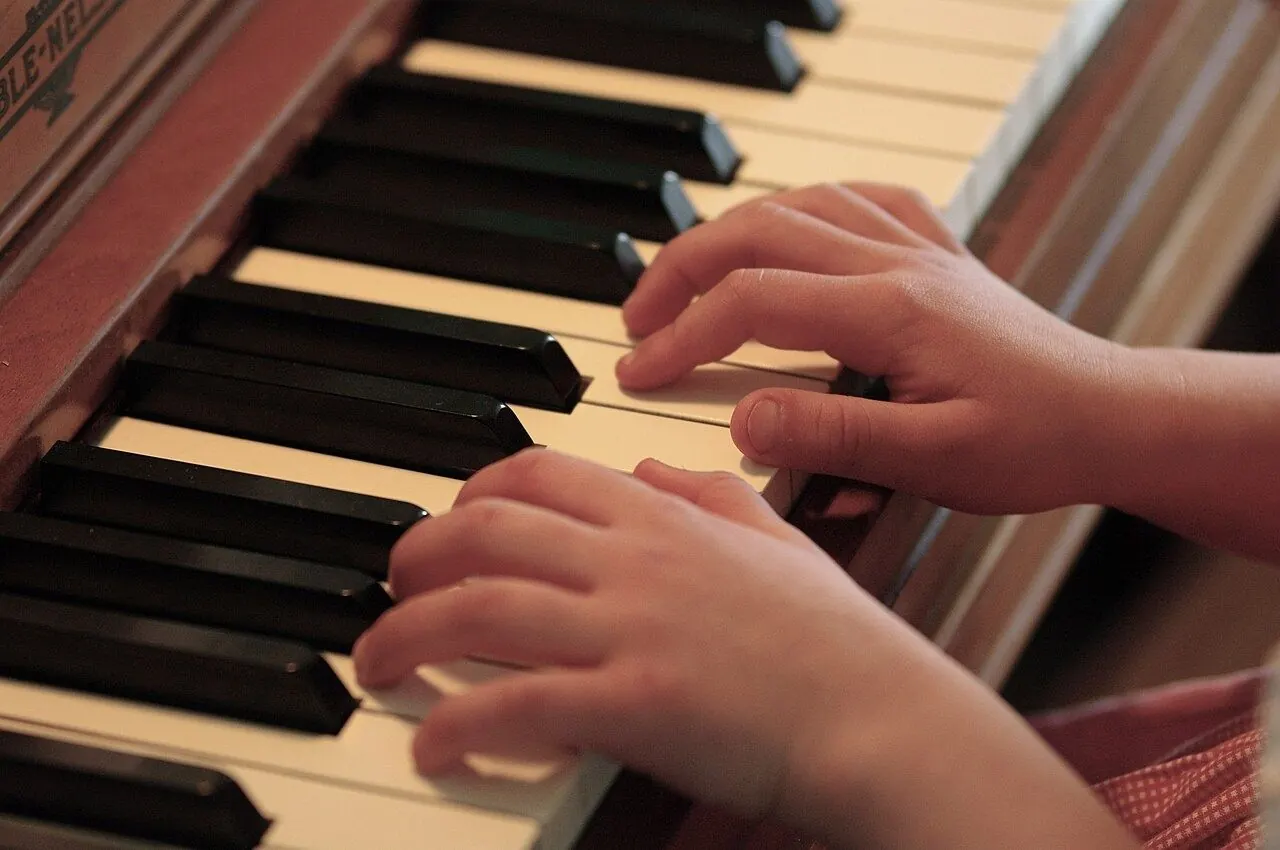 Young pianist practising at an upright piano with sheet music